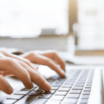 Zdjęcie przedstawia pracownika analizującego dane finansowe i ewidencyjne na laptopie. Fotografia nawiązuje do elektronicznego raportowania ewidencji środków trwałych i wartości niematerialnych i prawnych w strukturze JPK_ST_KR oraz planowanego odroczenia tego obowiązku.