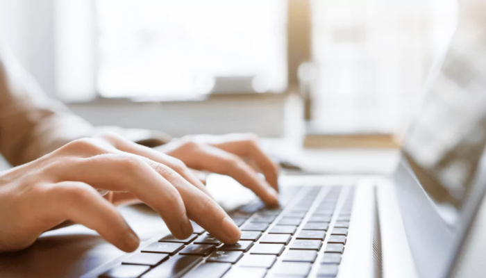 Zdjęcie przedstawia pracownika analizującego dane finansowe i ewidencyjne na laptopie. Fotografia nawiązuje do elektronicznego raportowania ewidencji środków trwałych i wartości niematerialnych i prawnych w strukturze JPK_ST_KR oraz planowanego odroczenia tego obowiązku.